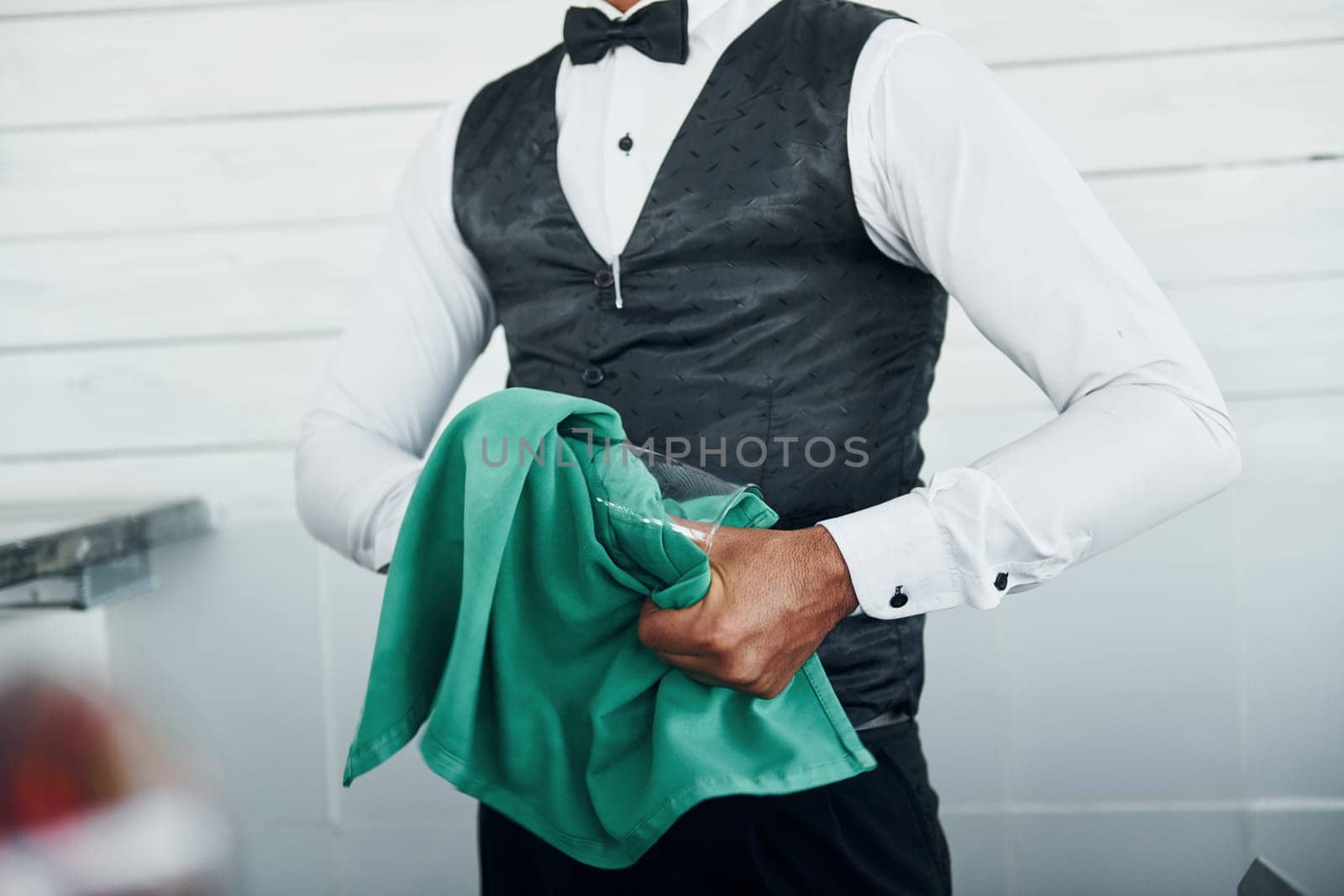 Black waiter in formal clothes is at his work outdoors at sunny daytime.