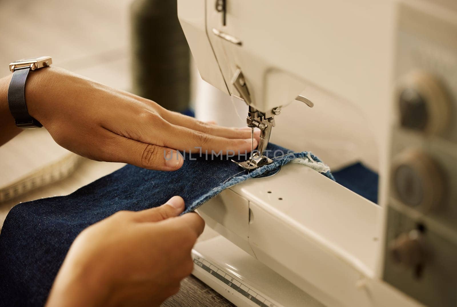 Creative designer stitching denim fabric on a sewing machine. Fashion designer using sewing machine. Tailor sewing demin material. Fashion entrepreneur sewing a piece of material in a sewing machine.