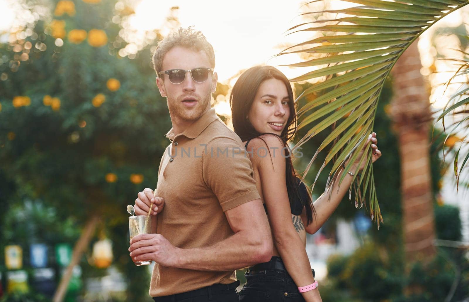 Man in sunglasses, woman in black bra. Happy young couple is together on their vacation. Outdoors at sunny daytime.