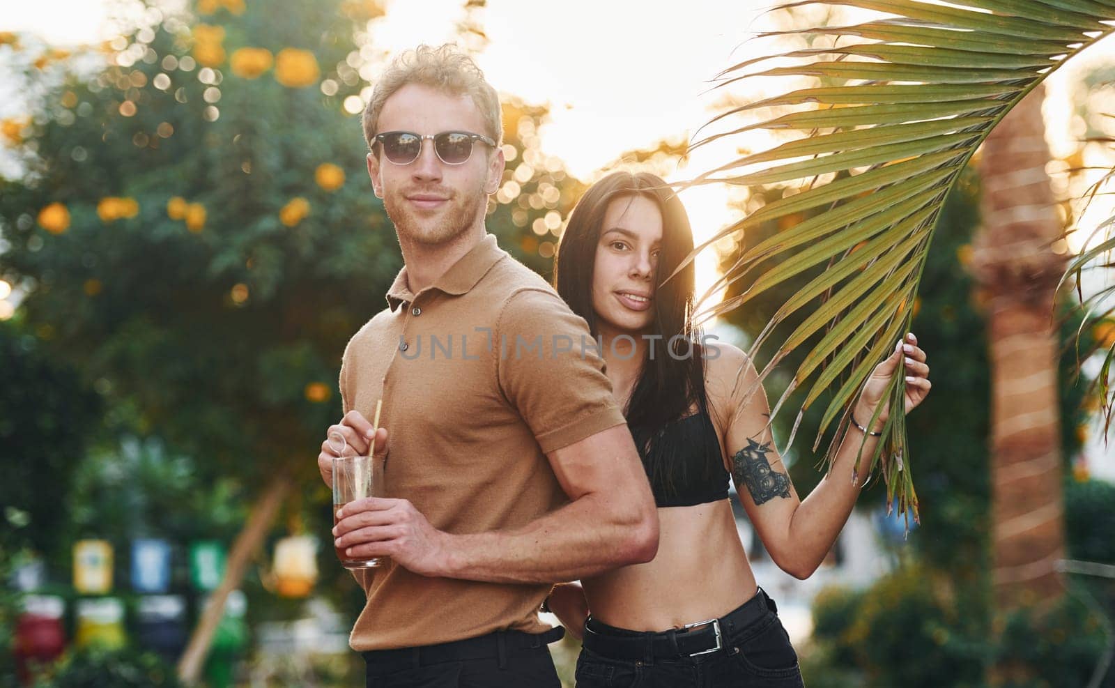 Man in sunglasses, woman in black bra. Happy young couple is together on their vacation. Outdoors at sunny daytime.