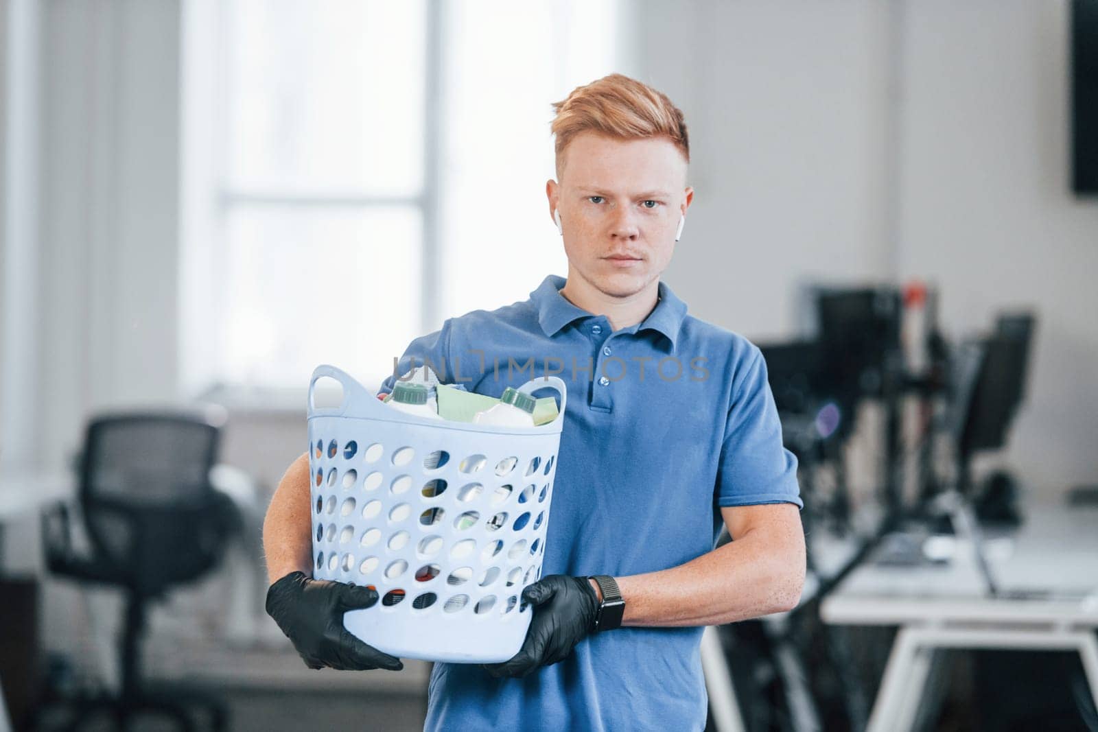 Portrait of young man in blue shirt and black protective gloves. Standing in the office.