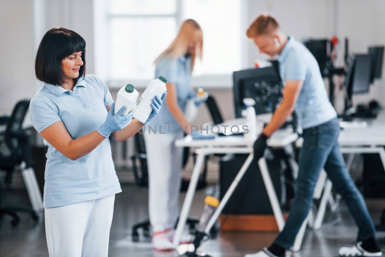 Group of workers clean modern office together at daytime.