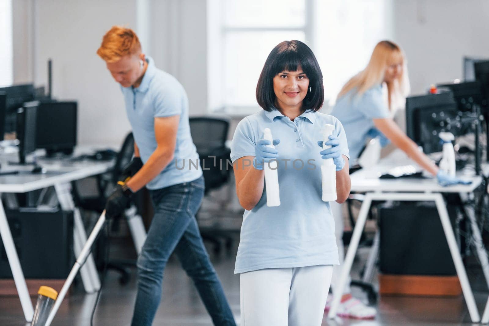 Group of workers clean modern office together at daytime.