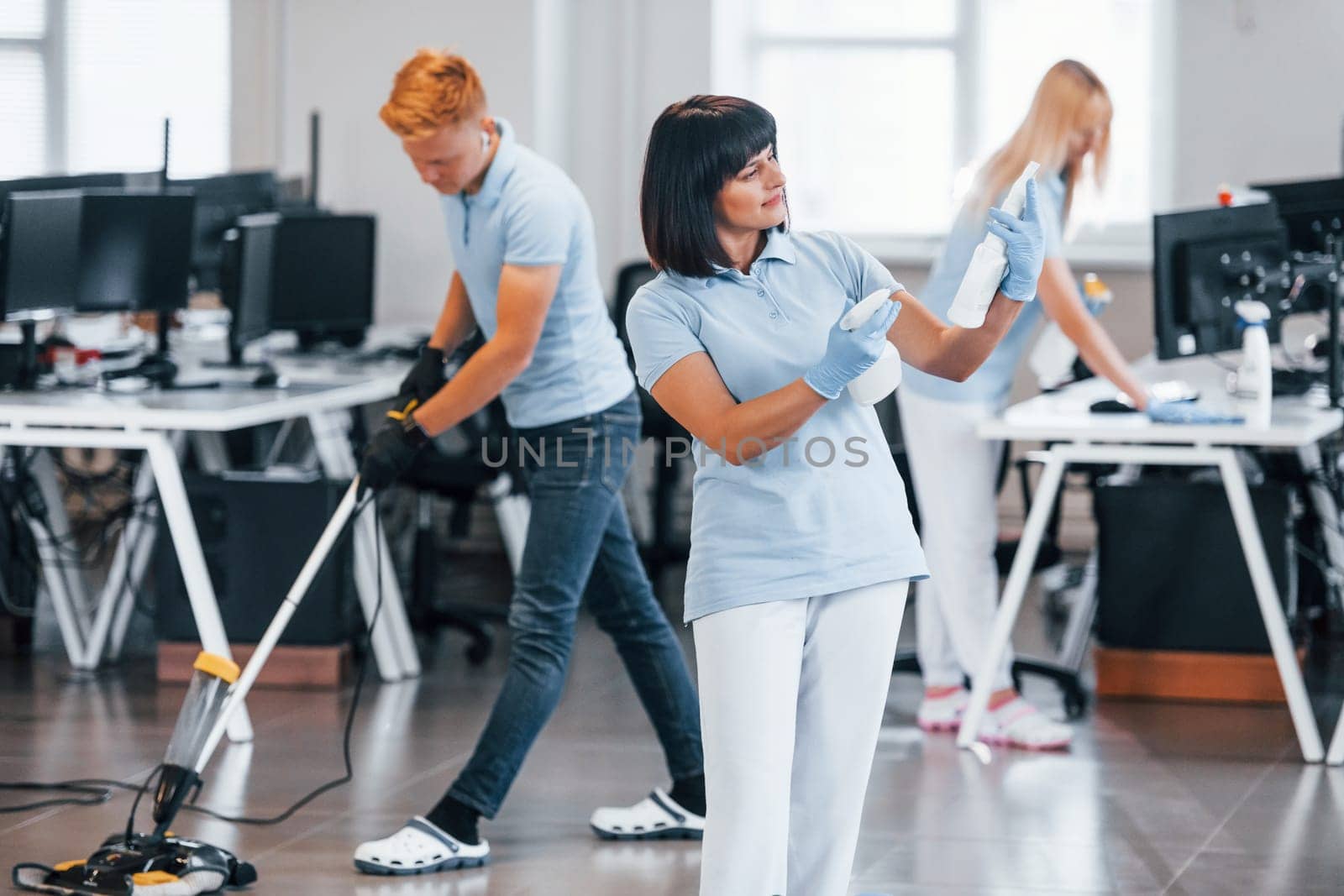 Group of workers clean modern office together at daytime.