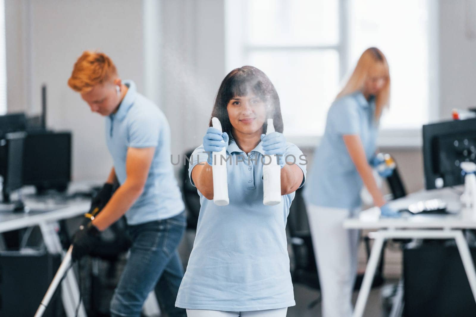 Group of workers clean modern office together at daytime.