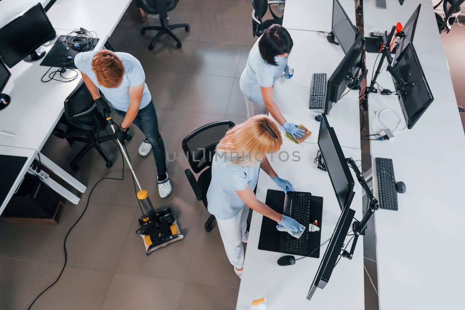 Top view. Group of workers clean modern office together at daytime.