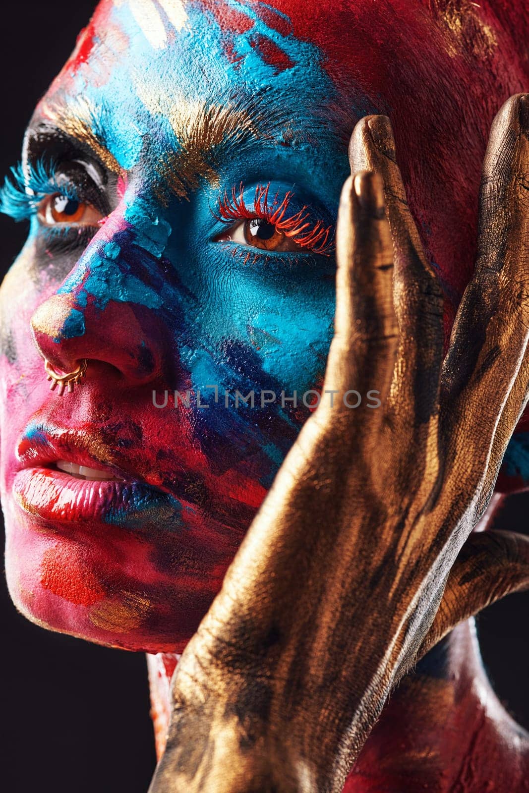 Dare to be different. an attractive young woman posing alone in the studio with paint on her face