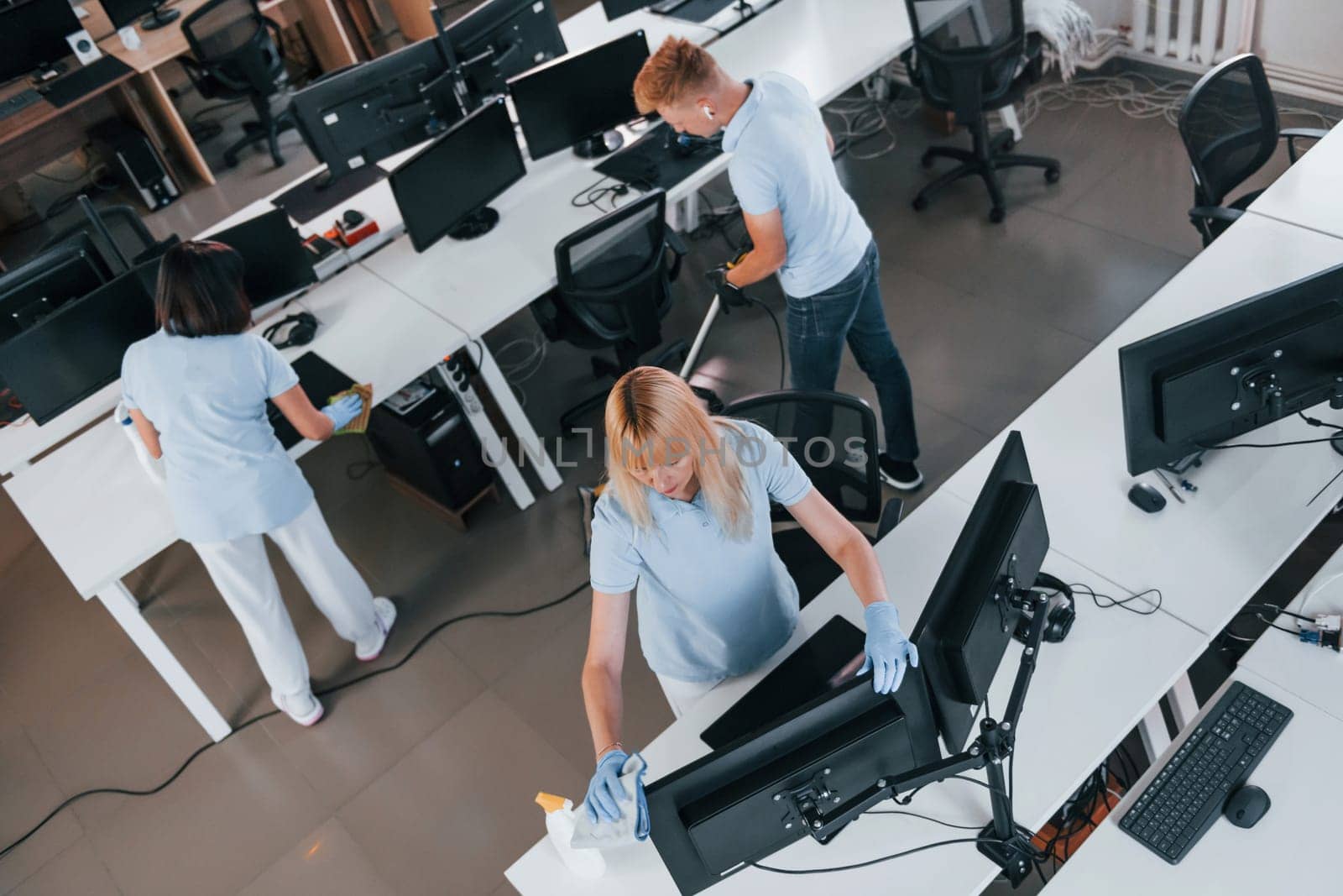Top view. Group of workers clean modern office together at daytime.