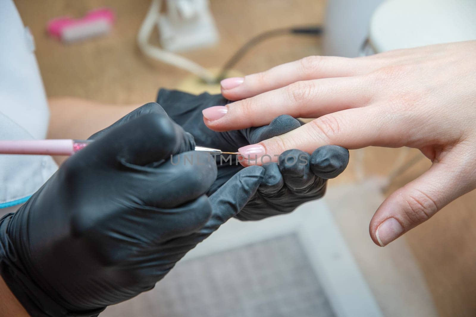 a master does a manicure to a client in a beauty salon and covers her nails by KaterinaDalemans