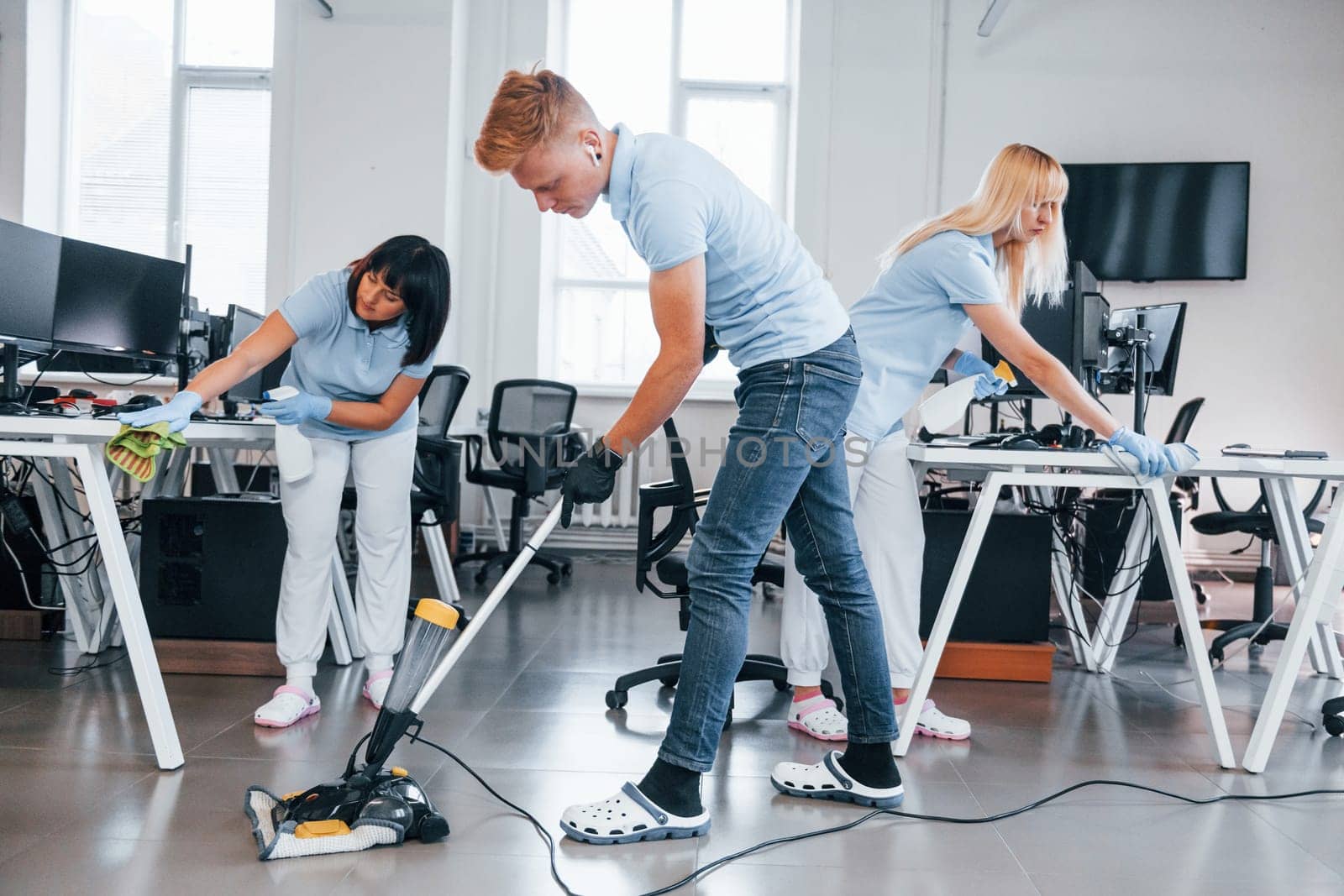 Concentrated at job. Group of workers clean modern office together at daytime.