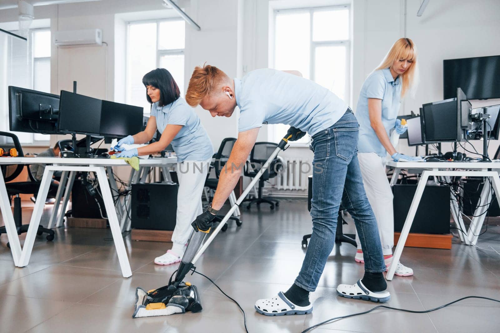 Concentrated at job. Group of workers clean modern office together at daytime.