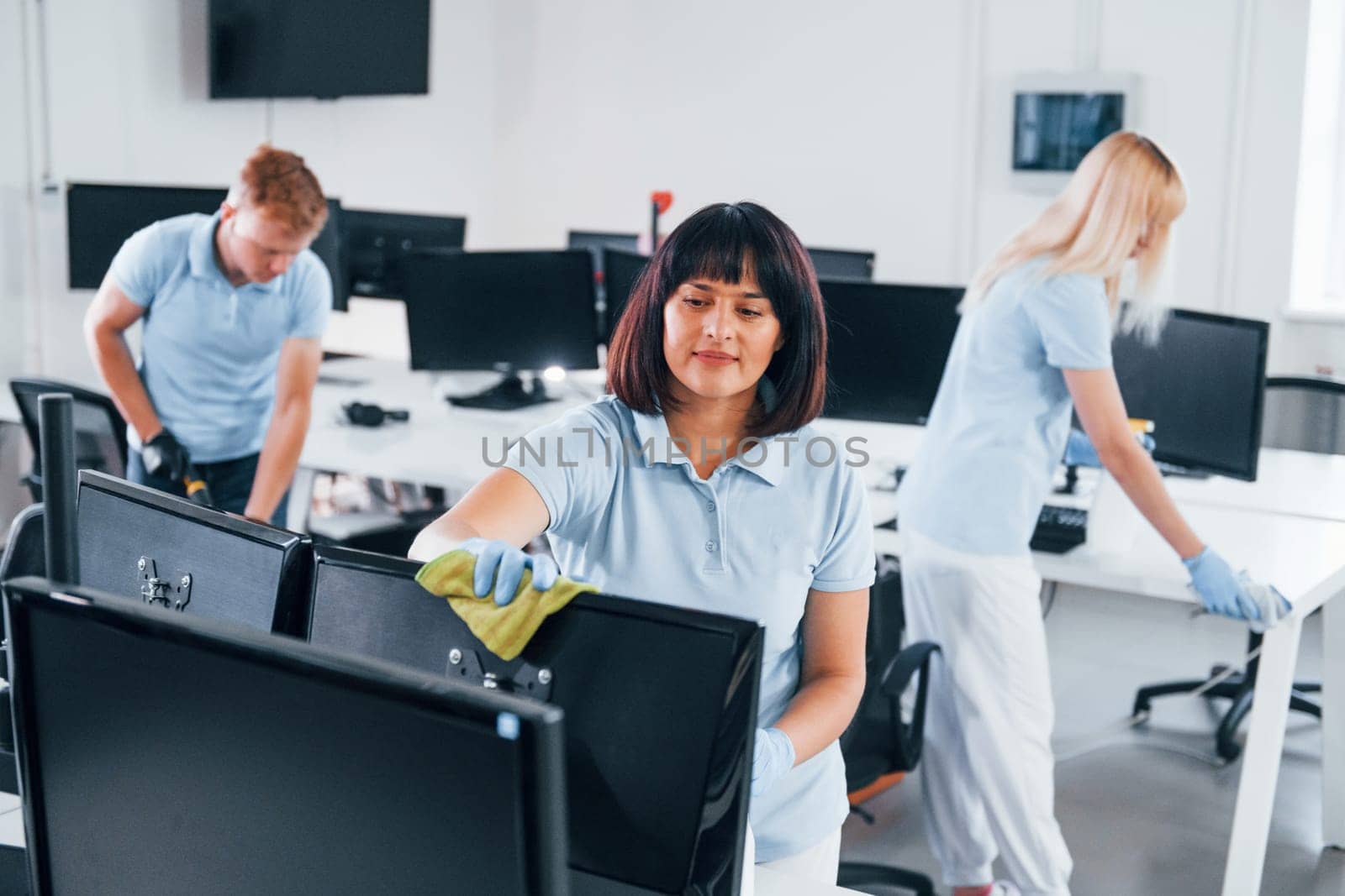 Group of workers clean modern office together at daytime.