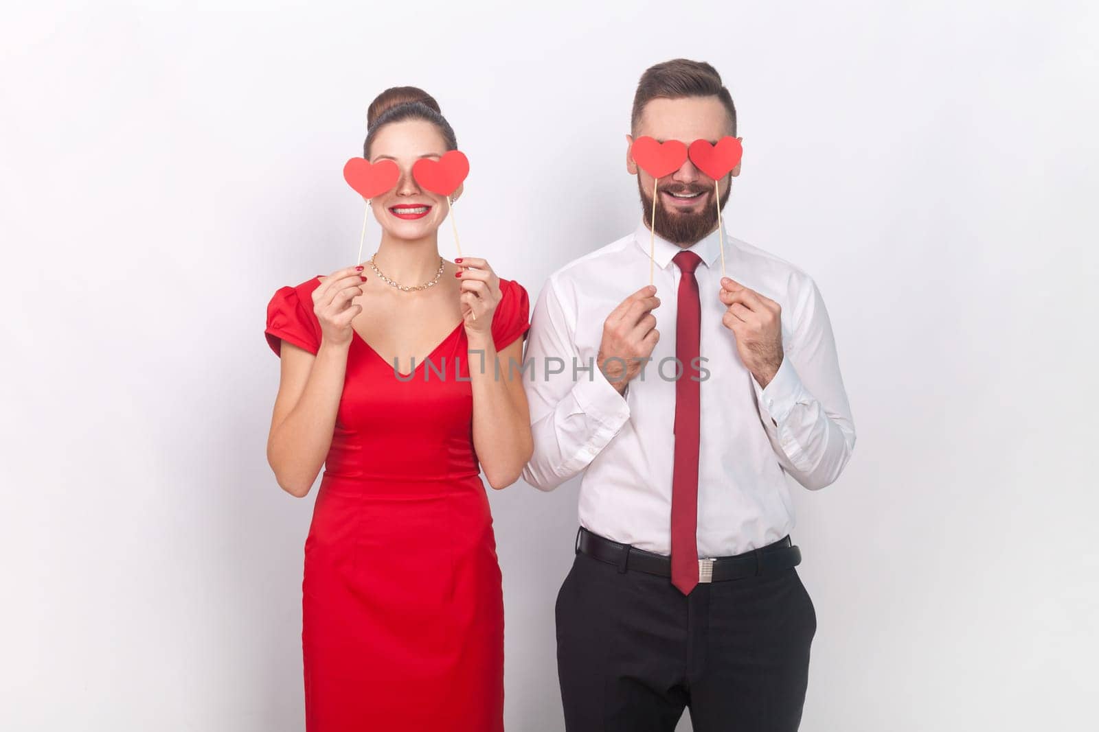 Romantic man and woman standing holding little hearts, covering eye with love symbols on stick. by Khosro1