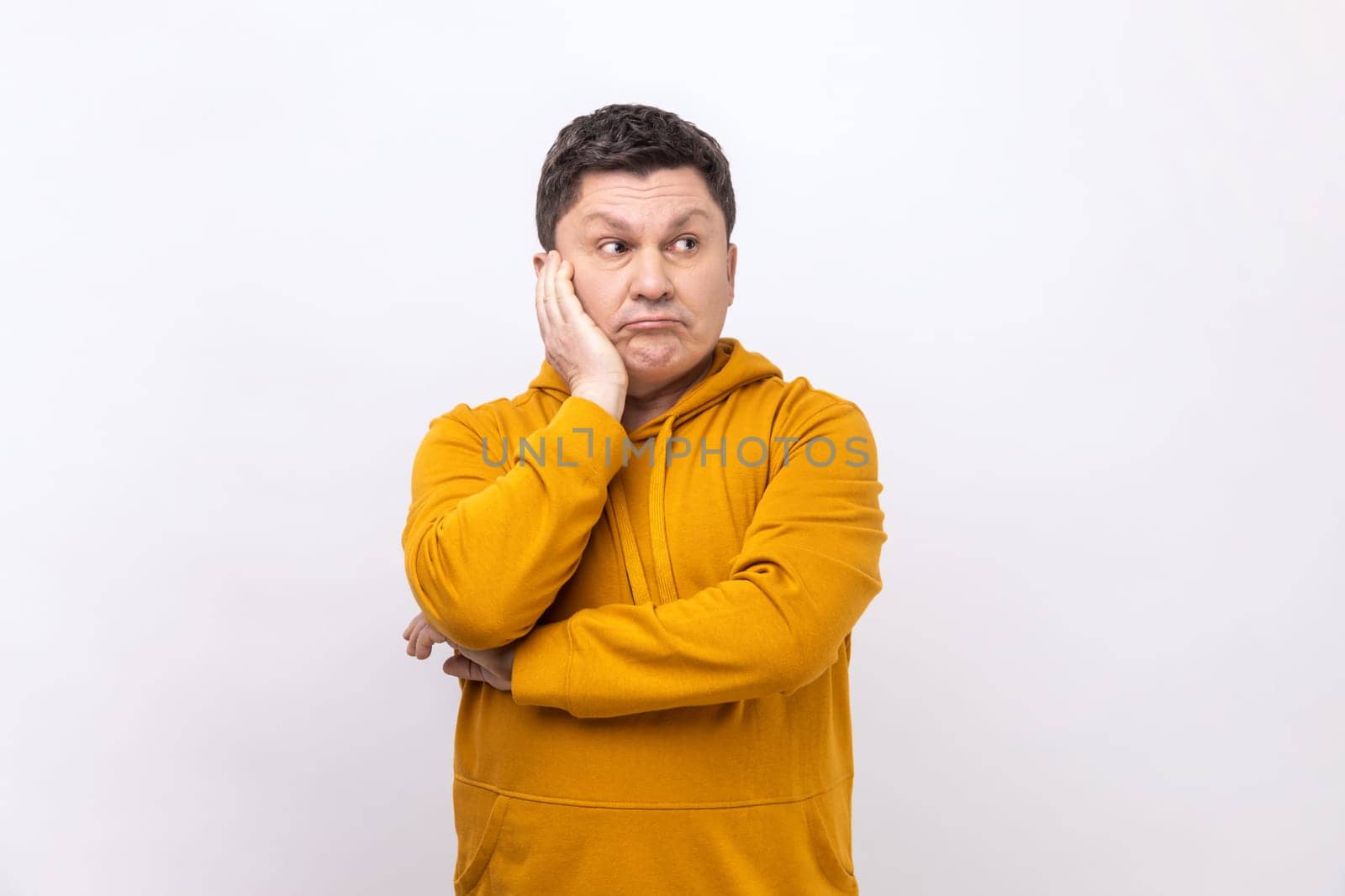 Doubtful middle aged man contemplating leaning head on hand, pondering difficult question, trying to make right choice, wearing urban style hoodie. Indoor studio shot isolated on white background.