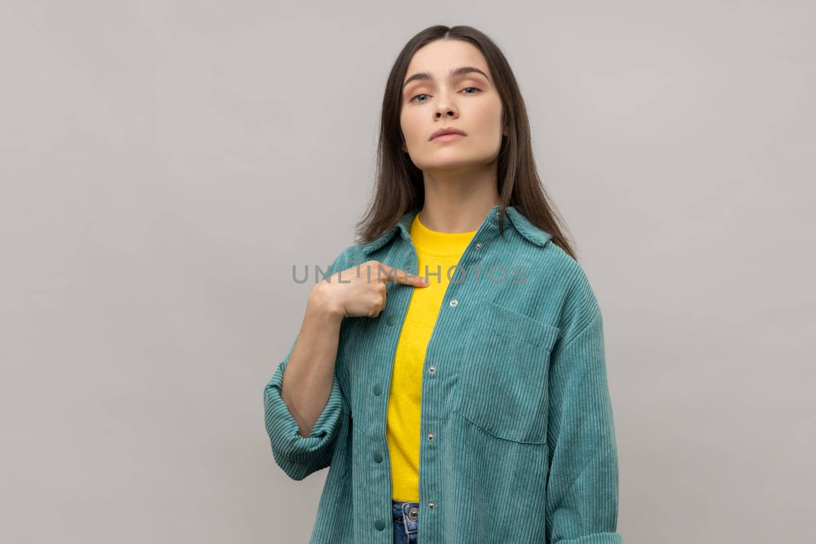 Confident egoistic woman pointing on herself with arrogance and satisfaction, proud of herself, bragging with achievements, wearing casual style jacket. Indoor studio shot isolated on gray background.