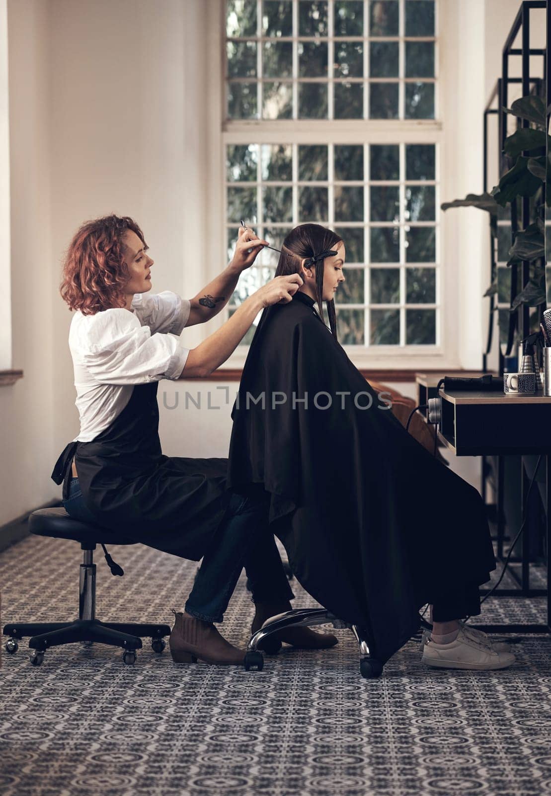 Blessed are the hairstylists, for they bring out the beauty in others. a young woman getting her hair cut in a salon