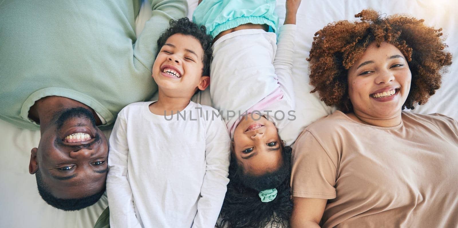 Portrait, top view and parents with children in bed enjoy morning for bonding, quality time and relaxing. Black family, home and happy mother, father and kids in bedroom for affection, trust and love.