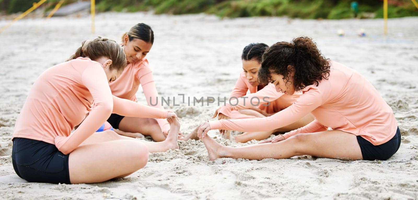 Beach, volleyball and women stretching legs ready to play match, competition and sports games. Teamwork, fitness and female players stretch body for warm up practice, training and exercise on sand by YuriArcurs