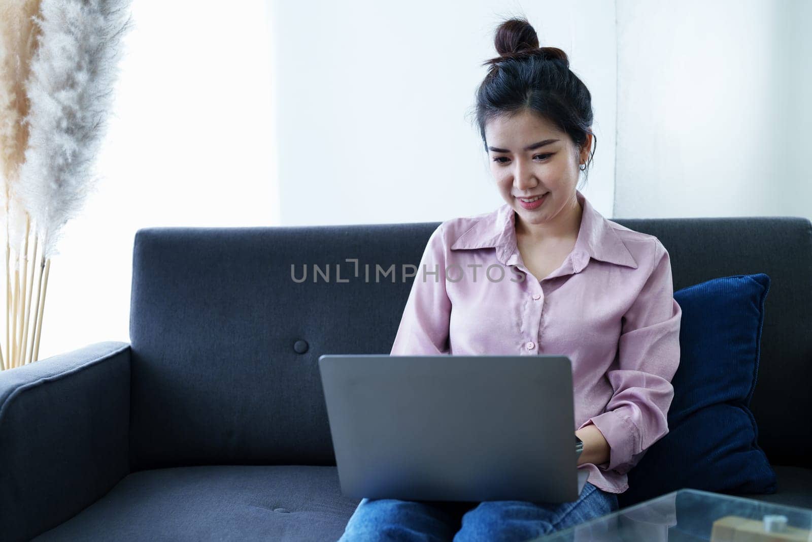 Portrait of a self-employed Asian woman using a computer at home by Manastrong