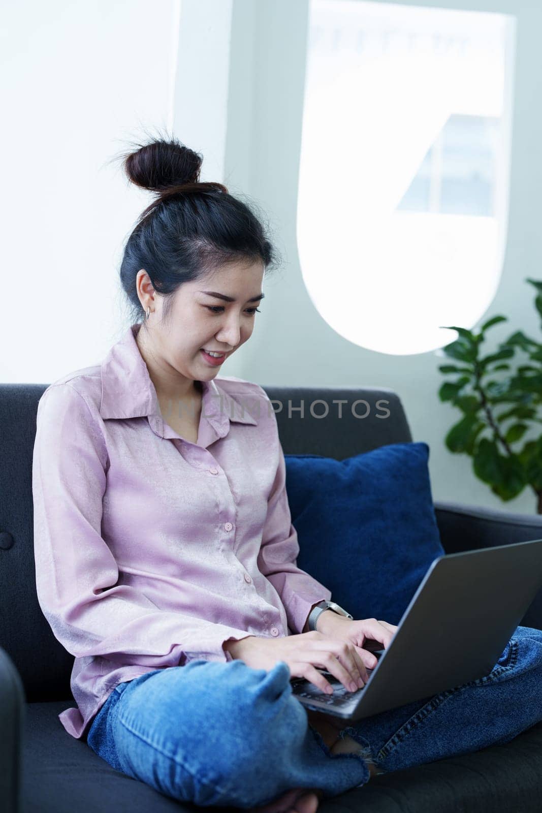 Portrait of a self-employed Asian woman using a computer at home by Manastrong