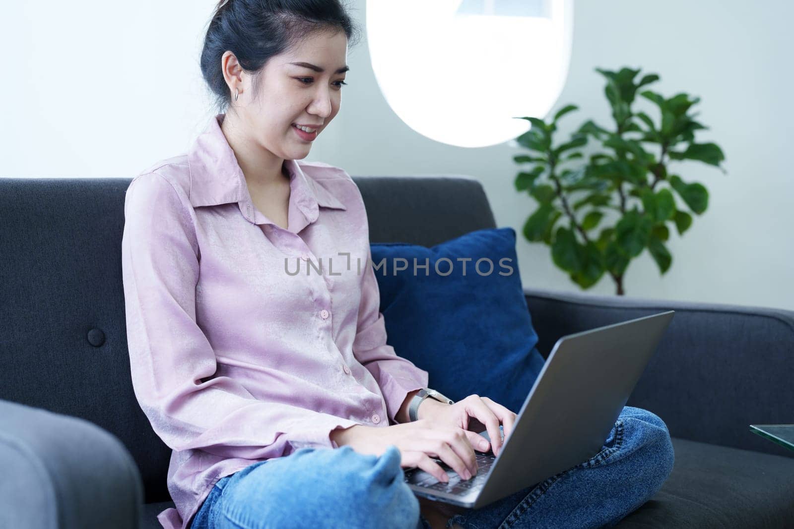 Portrait of a self-employed Asian woman using a computer at home by Manastrong