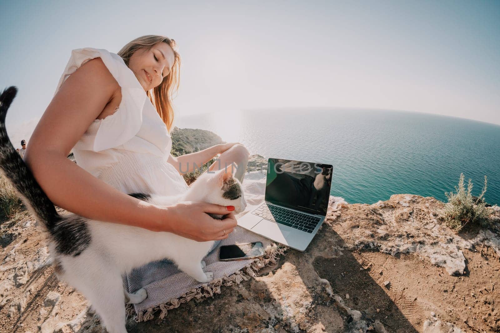 Woman sea laptop. Business woman in yellow hat working on laptop by sea. Close up on hands of pretty lady typing on computer outdoors summer day. Freelance, digital nomad, travel and holidays concept.