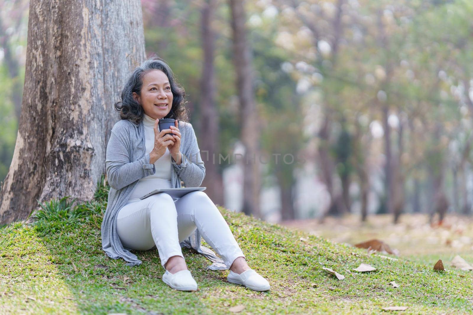 Cheerful overjoyed woman happy and enjoying peaceful beautiful in park and holding hot coffee by itchaznong