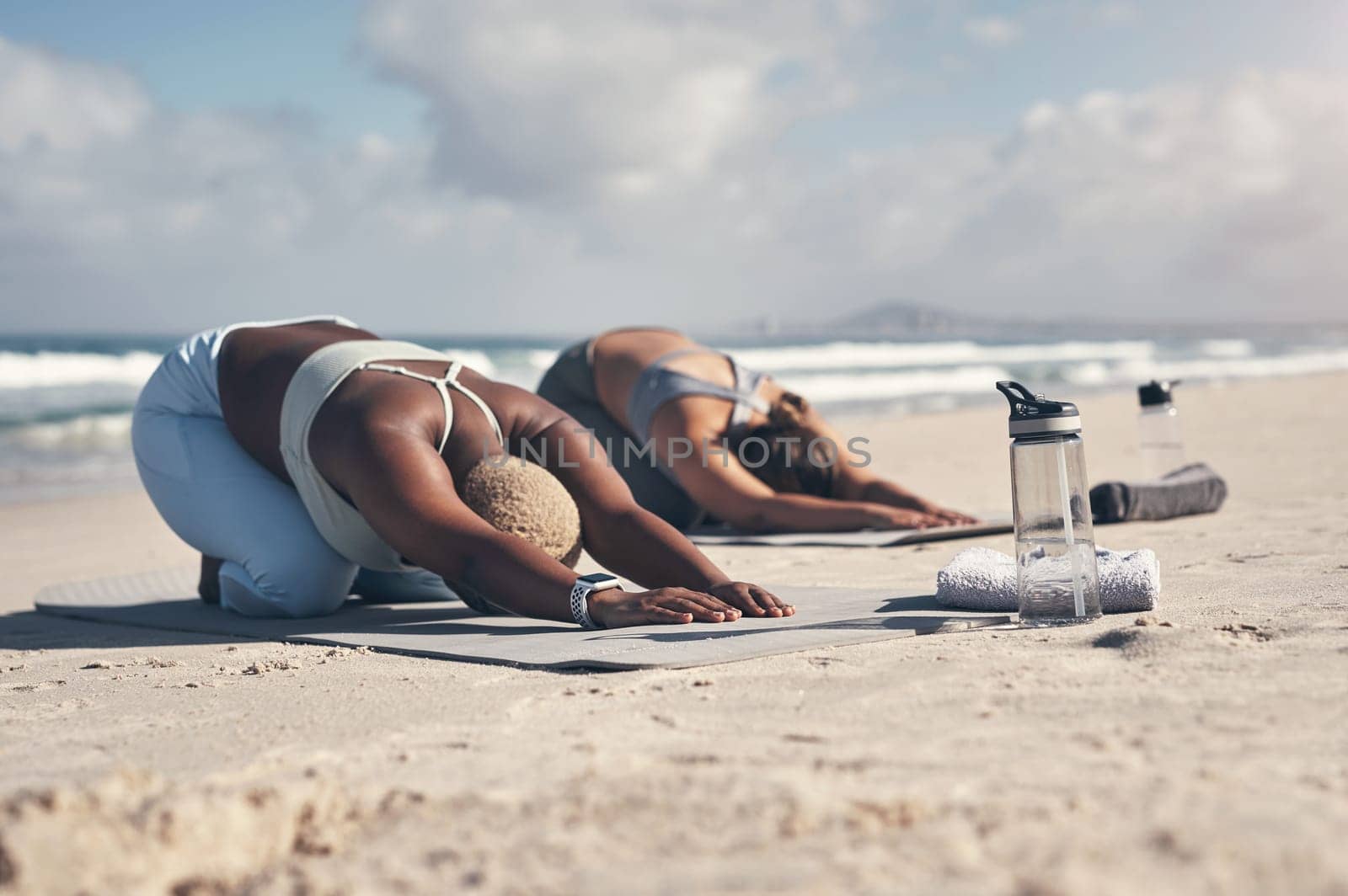 Yoga is like a massage, it relaxes the whole body. two young women practicing yoga on the beach. by YuriArcurs