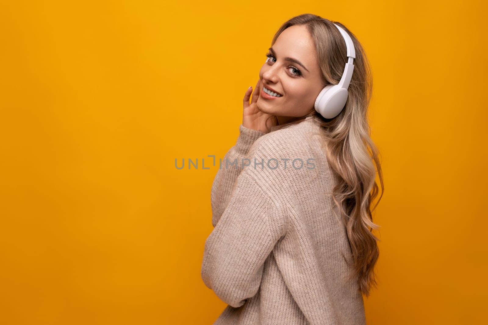 a girl with big headphones listens to her favorite music on a yellow background by TRMK