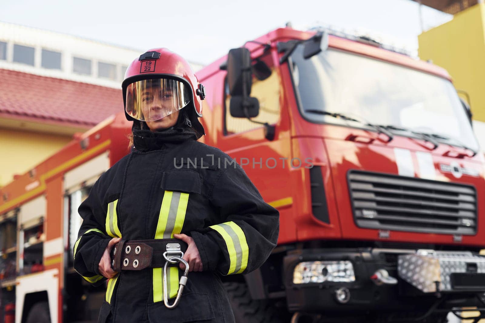 Female firefighter in protective uniform standing near truck.