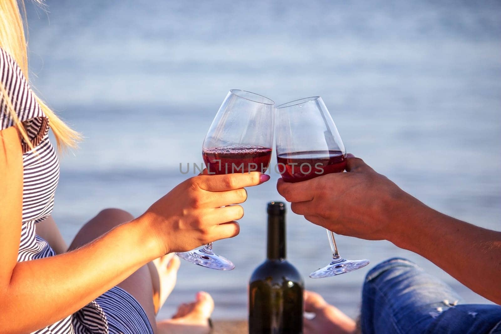 Romantic couple enjoying wine by the sea. Selective focus
