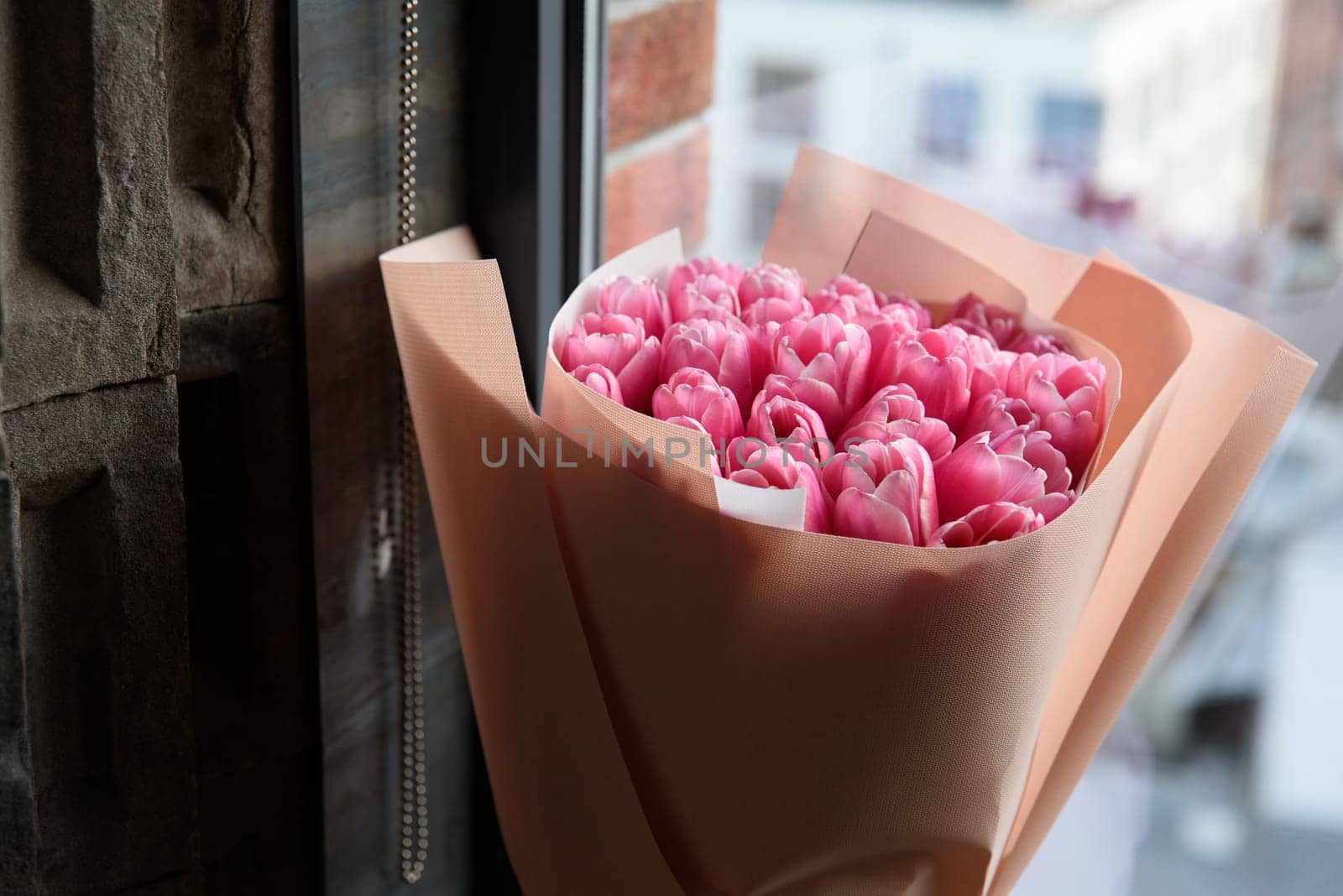 beautiful pink tulips bouquet in wrapping paper on a windowsill by Ashtray25