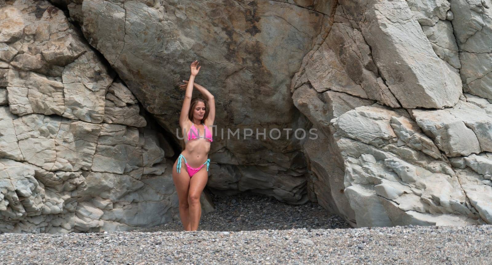 Woman travel sea. Young Happy woman in a long red dress posing on a beach near the sea on background of volcanic rocks, like in Iceland, sharing travel adventure journey
