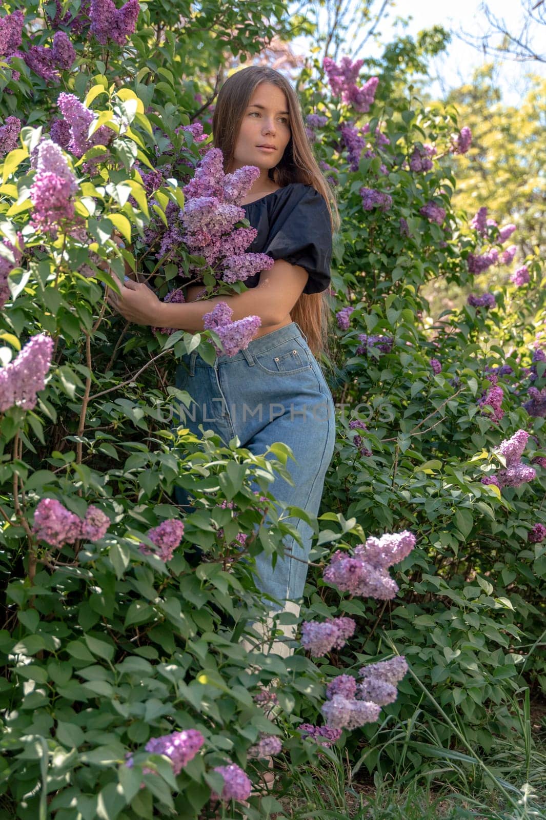 portrait of young woman with long hair outdoors in blooming lilac garden by Matiunina