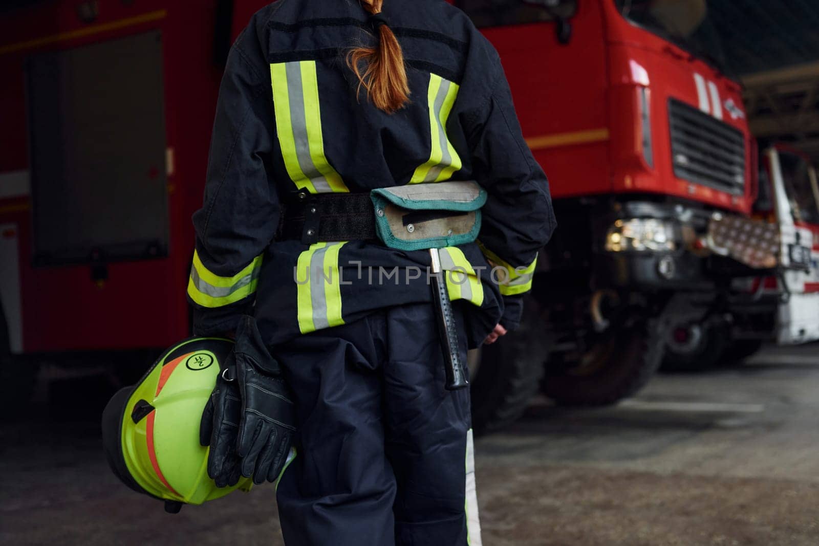 Close up view. Female firefighter in protective uniform standing near truck.