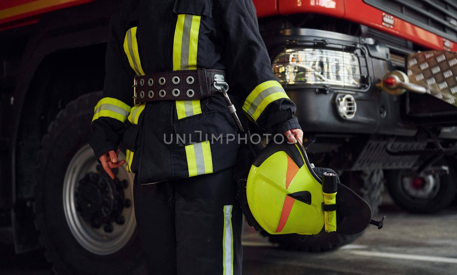Close up view. Female firefighter in protective uniform standing near truck.