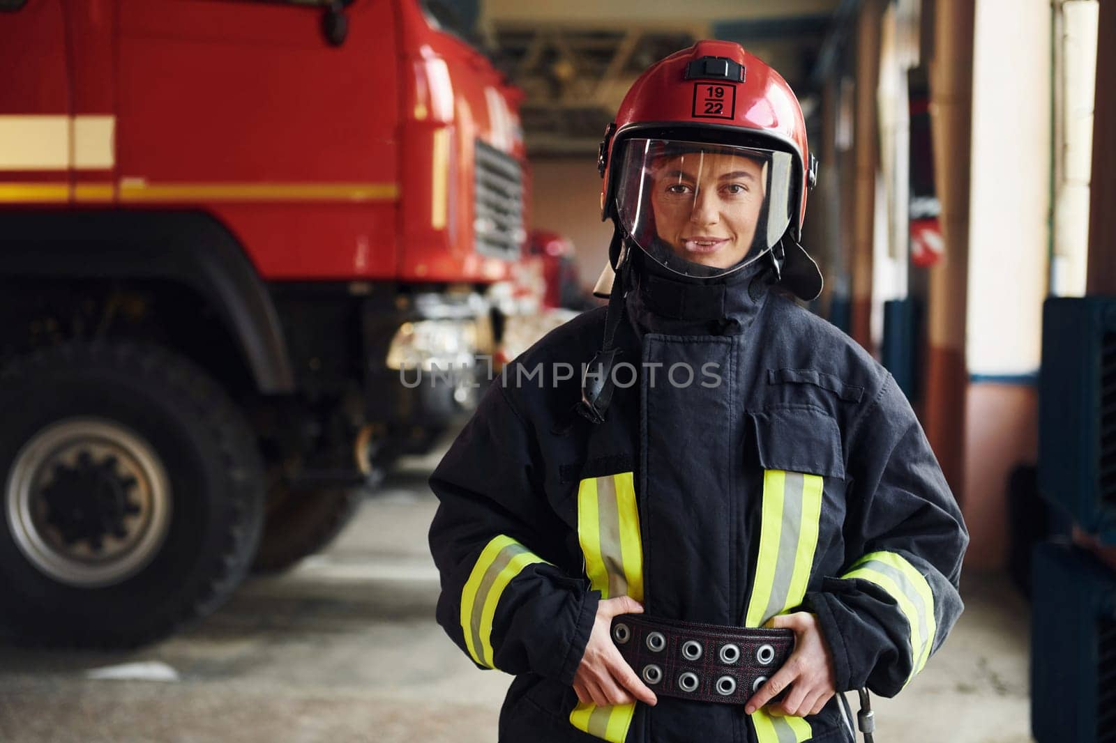 Female firefighter in protective uniform standing near truck.