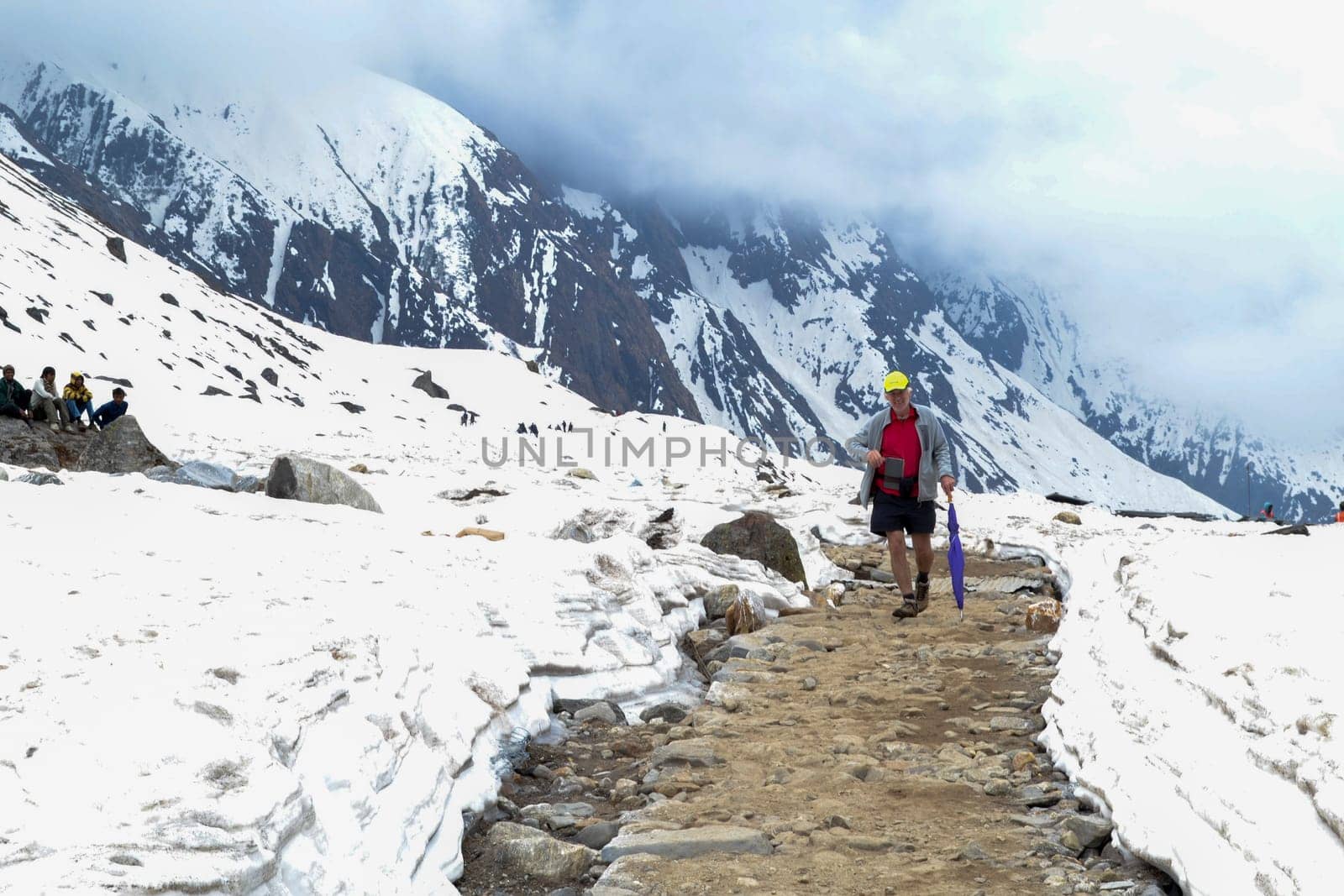 Rudarprayag, Uttarakhand, India, May 18 2014, A foreigner passing through the Kedarnath trek amidst snow. Kedarnath is a town in the Indian state of Uttarakhand and has gained importance because of Kedarnath Temple.
