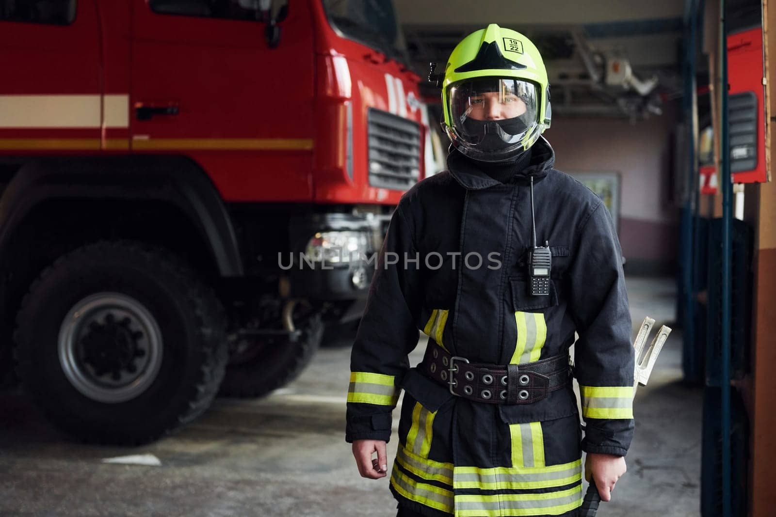 Male firefighter in protective uniform standing near truck.