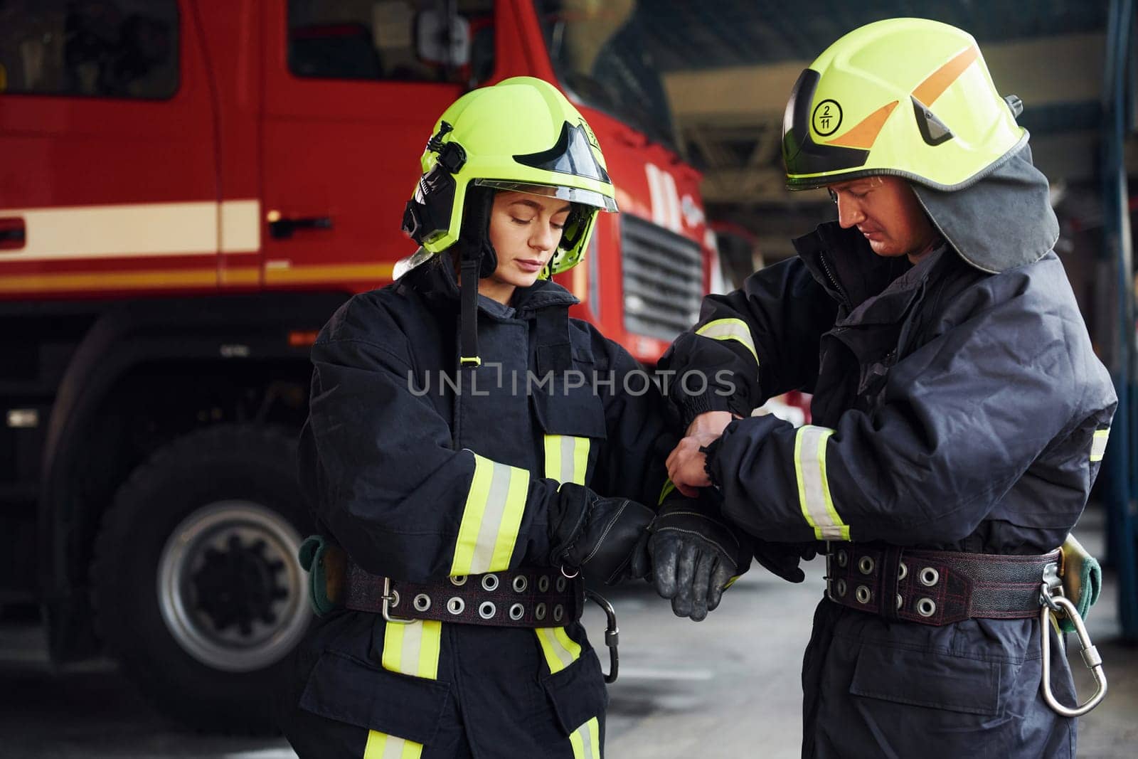 Male and female firefighters in protective uniform standing together.