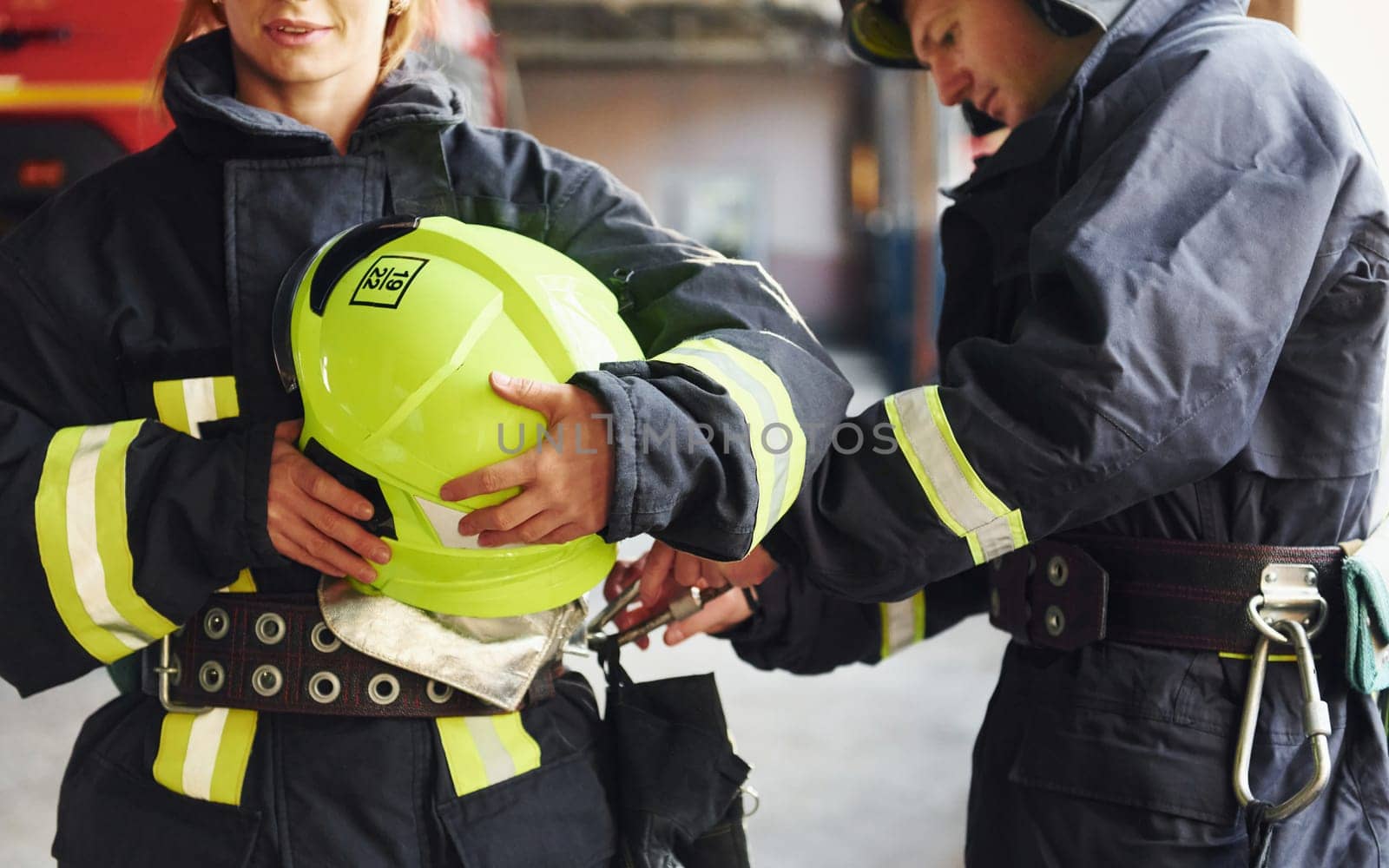 Male and female firefighters in protective uniform standing together.