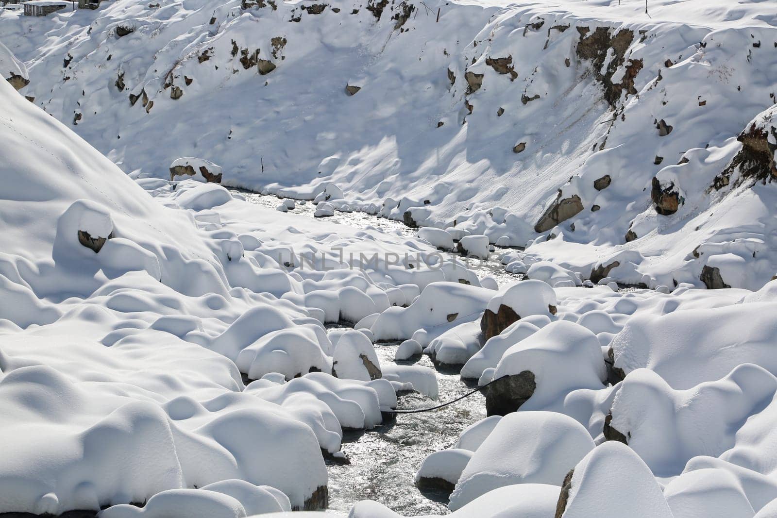 Snow covered river bank and stones in Himalaya. by stocksvids