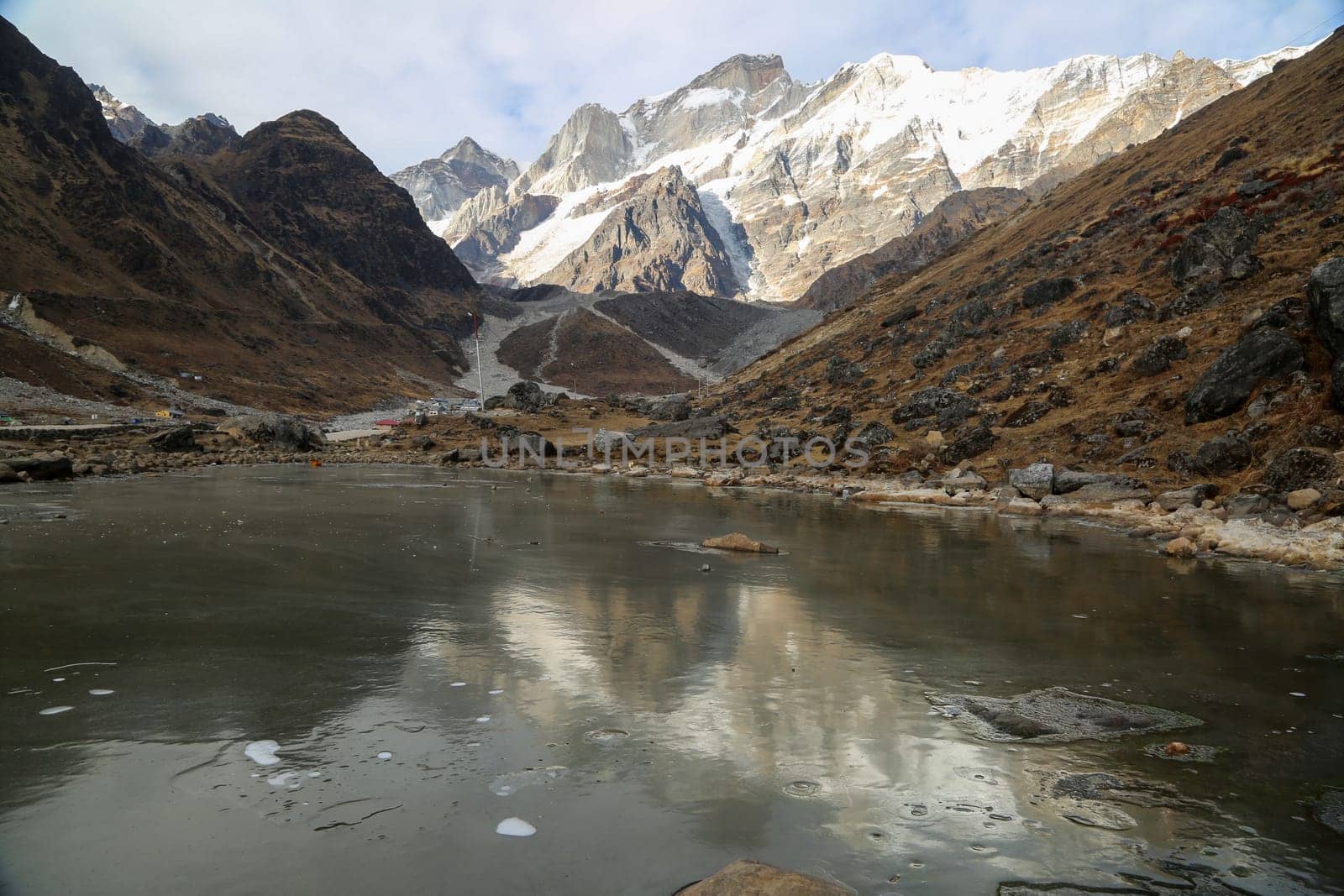 Snow covered peak and a lake in high altitude of Himalaya. by stocksvids