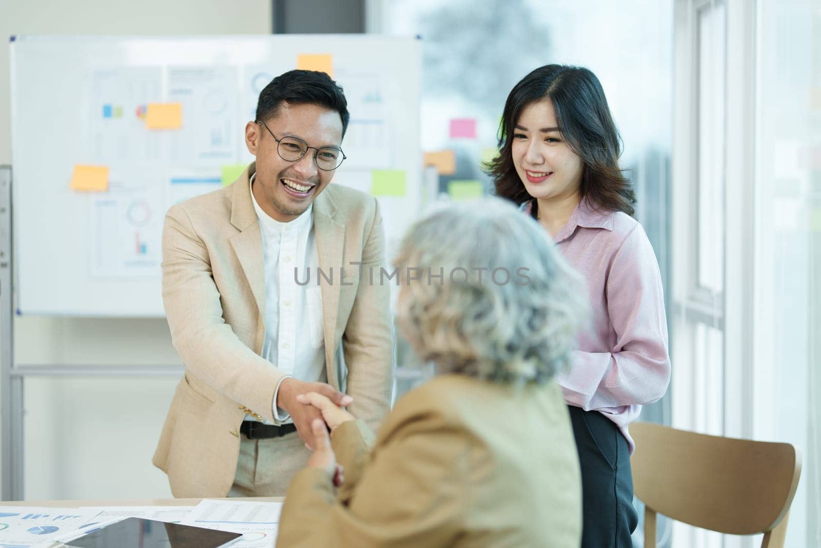 Asian entrepreneurs handshakes to congratulate the agreement between the two companies to enhance investment and financial strength. deal concept by Manastrong