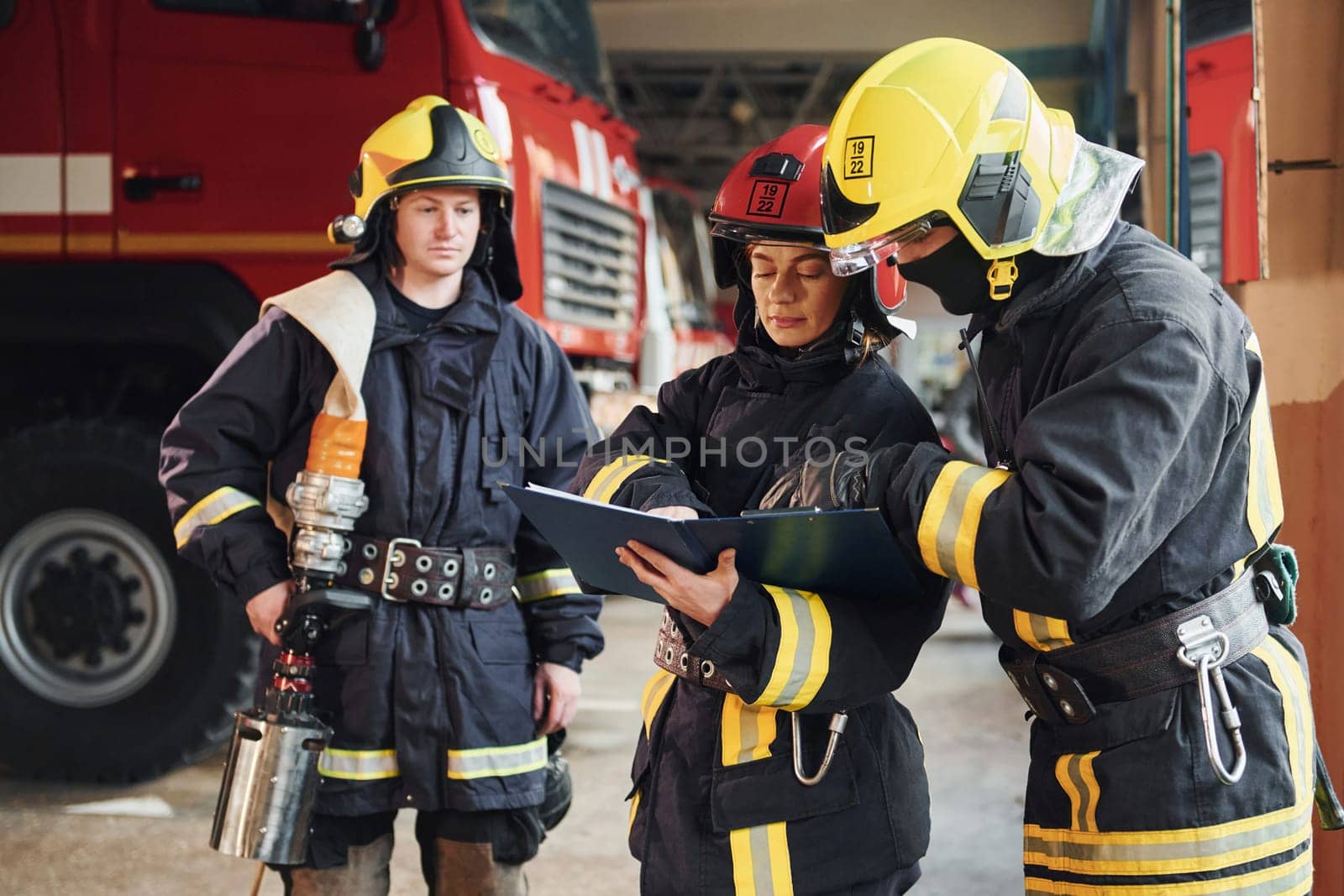 With notepad. Group of firefighters in protective uniform that is on station.