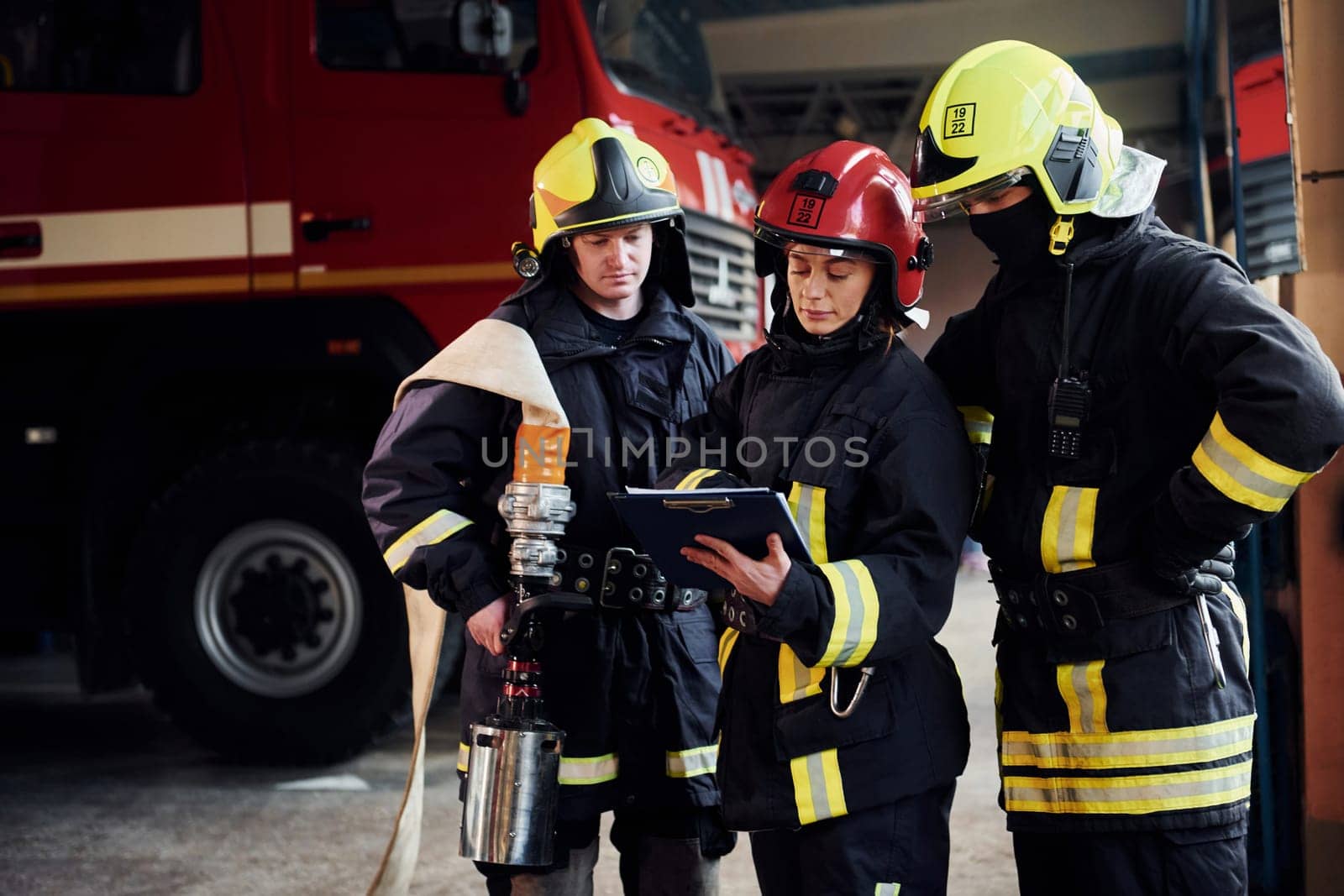 With notepad. Group of firefighters in protective uniform that is on station.