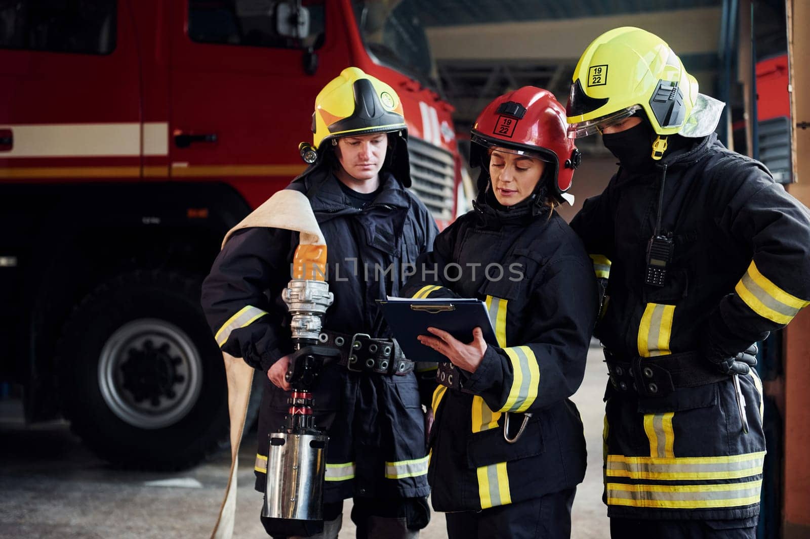 With notepad. Group of firefighters in protective uniform that is on station.