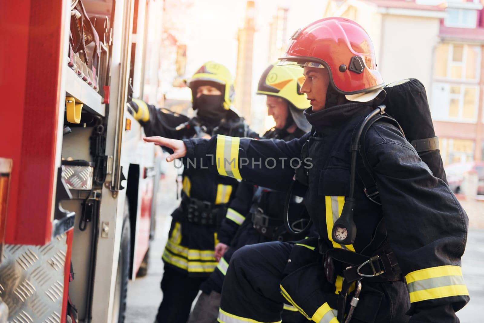 Group of firefighters in protective uniform that outdoors near truck.