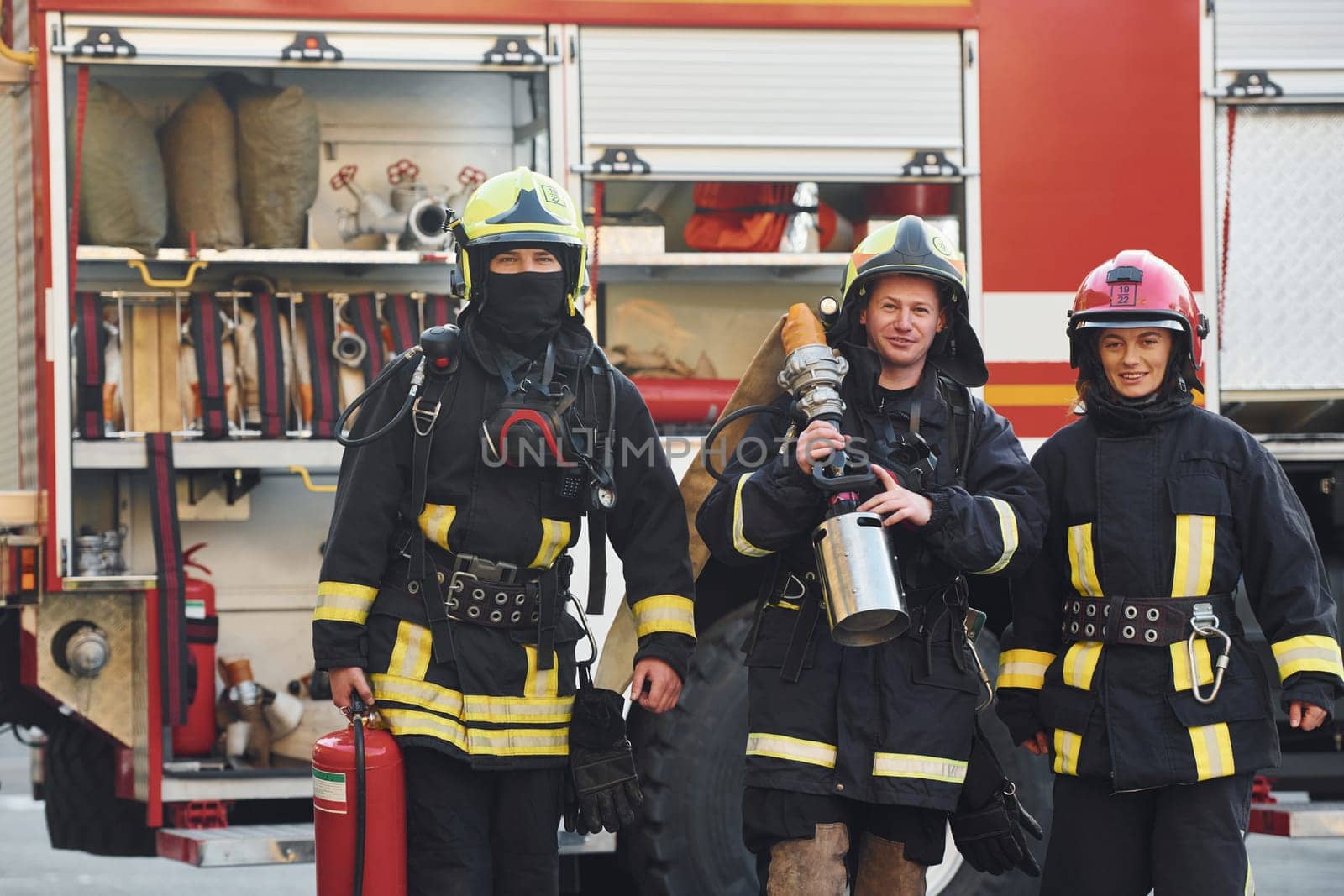 Group of firefighters in protective uniform that outdoors near truck.