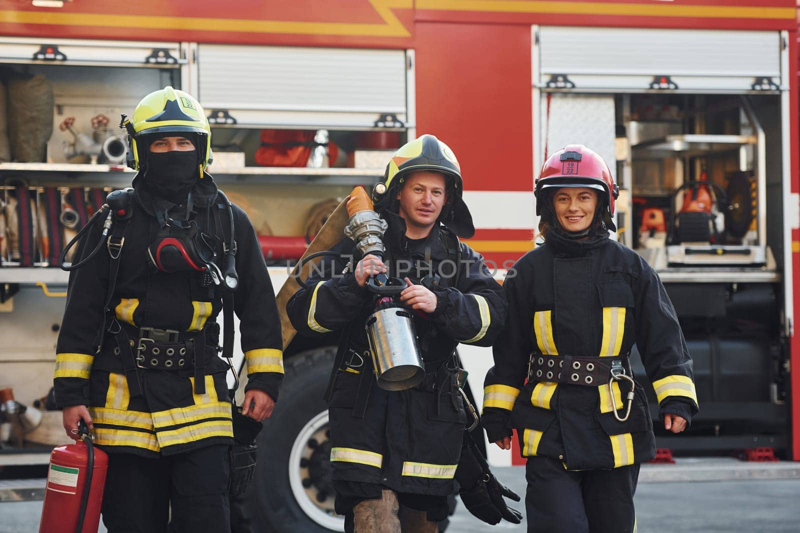 Group of firefighters in protective uniform that outdoors near truck.